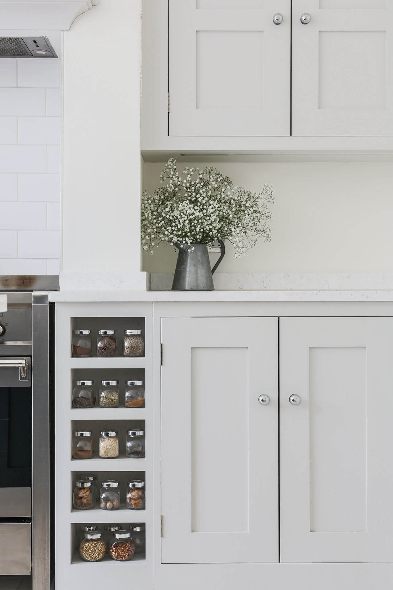 Open plan white Shaker kitchen with bespoke spice rack and Farrow & Ball Ammonite painted cabinets