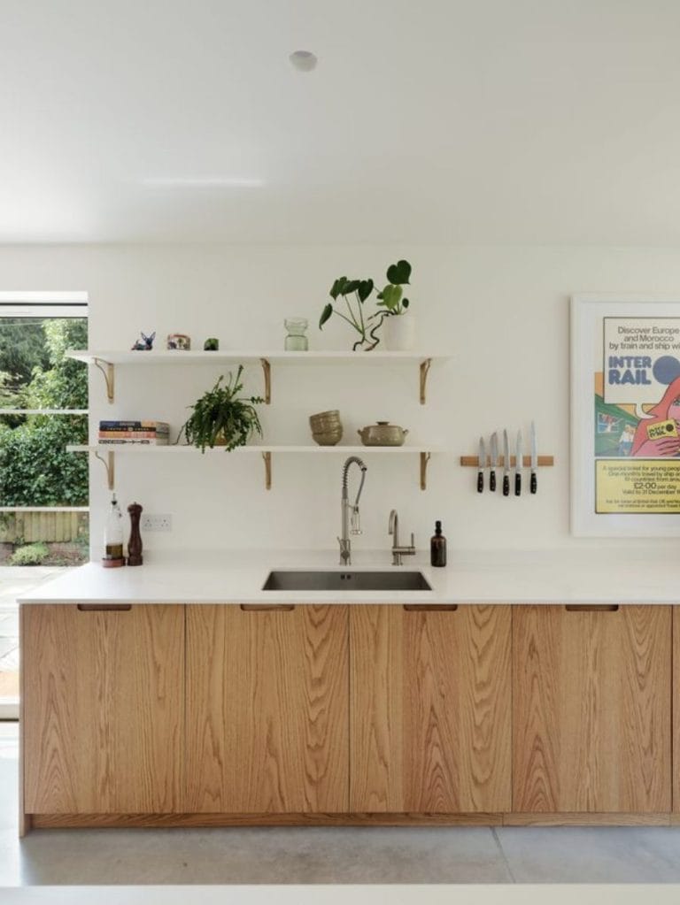 Sink area with brushed steel tap, white Caesarstone worktop and floating display shelves.