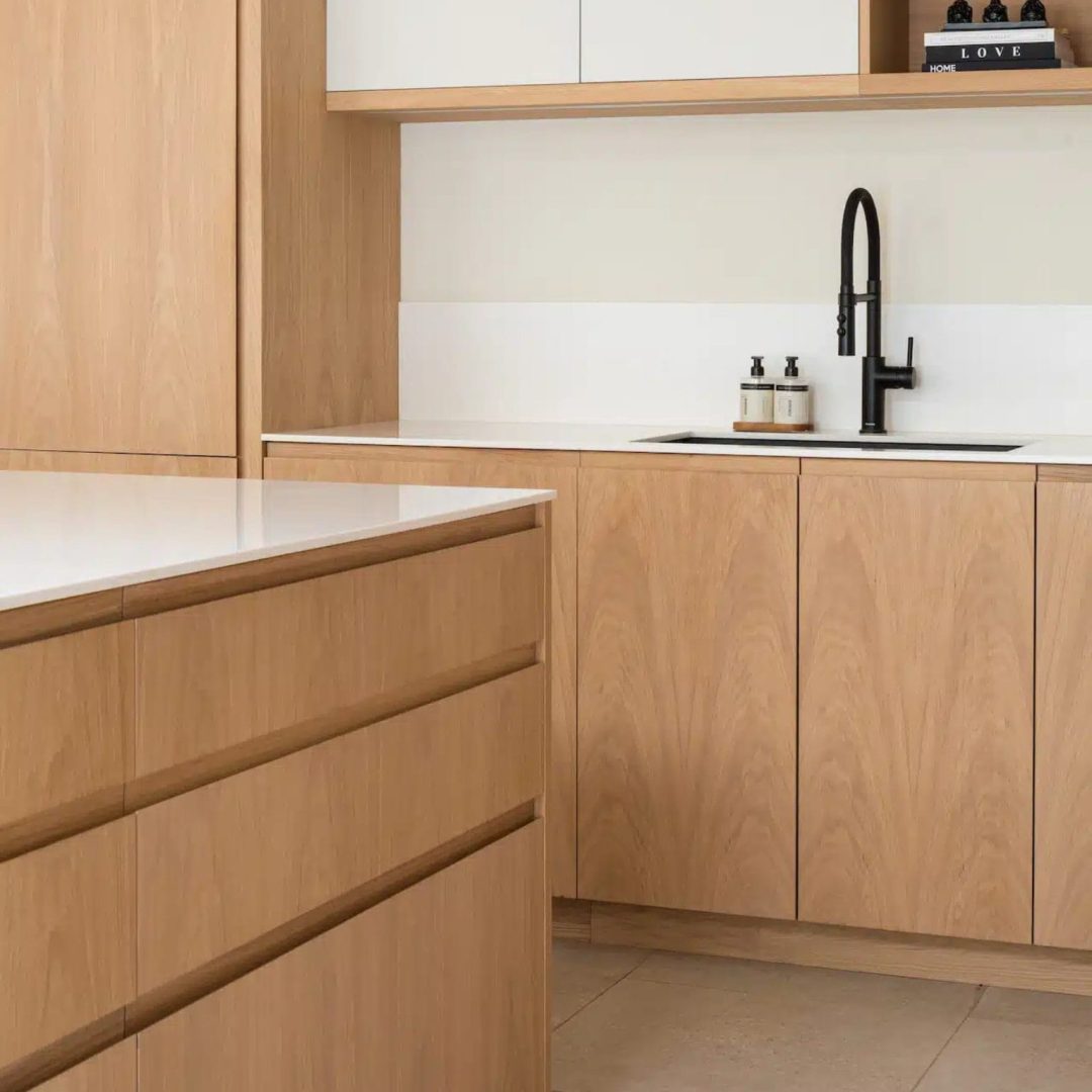 Scandinavian-style kitchen with oak veneer bespoke kitchen units and integrated bespoke kitchen handle design on a central island by Sustainable Kitchens.