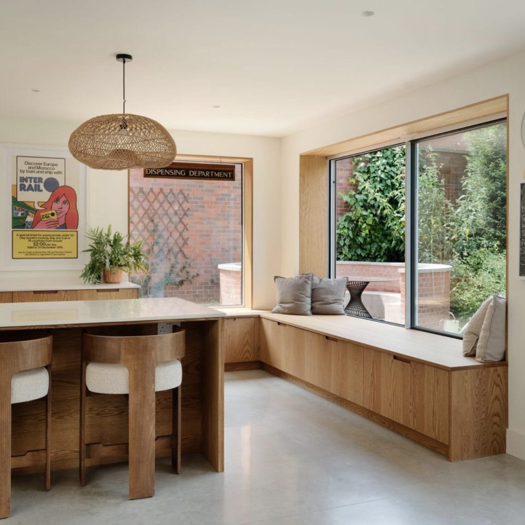 Large kitchen island with book storage, pendant lighting and oak cabinets with open shelving above.