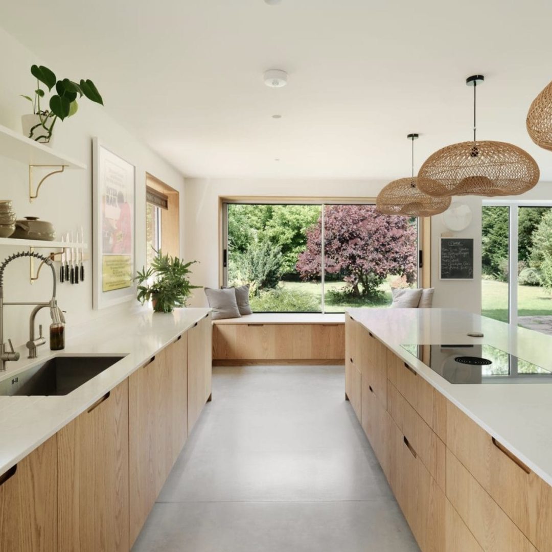 Bright open-plan kitchen with oak cabinetry, Caesarstone worktops and views out to a leafy garden.